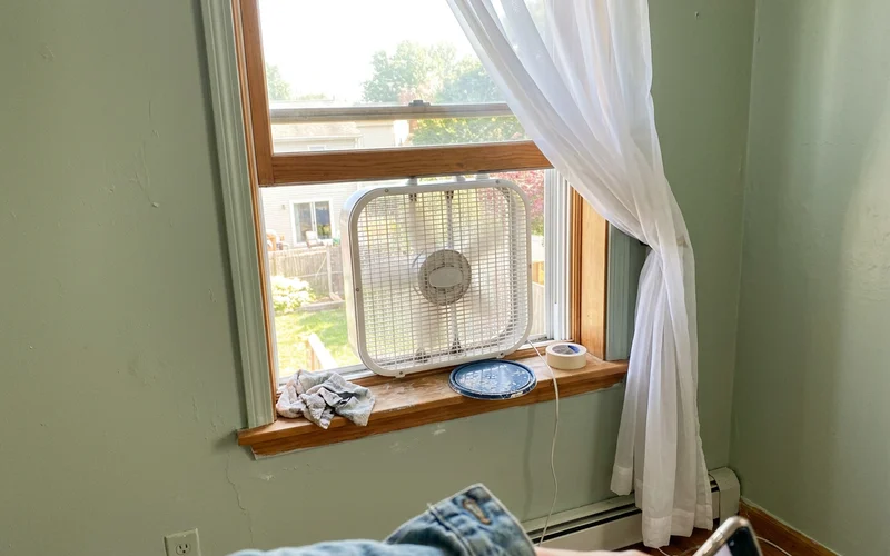 Box fan in an open window of a freshly painted bedroom