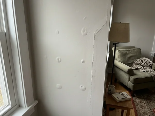 Before: living room wall with nail pops and a cracked tape joint