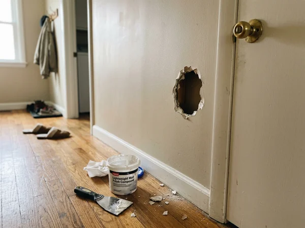 Fist-size hole in hallway drywall before repair