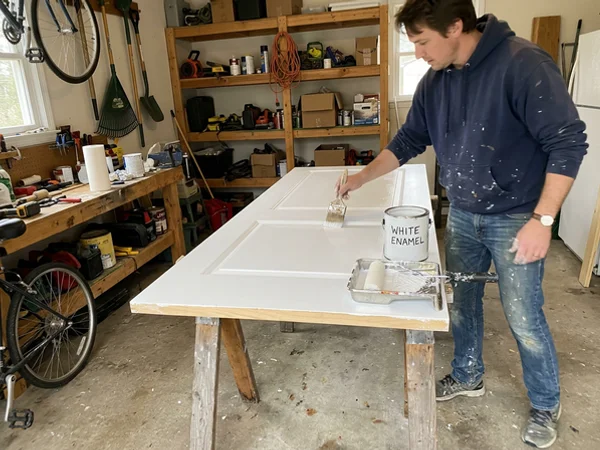 Brushing an interior door with white trim enamel