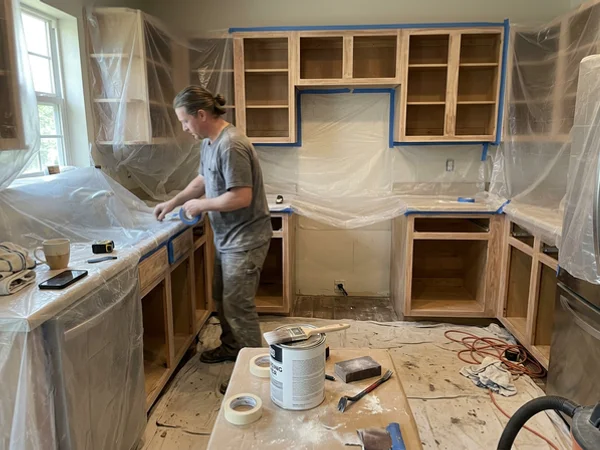 Kitchen masked in plastic with cabinet boxes ready for primer