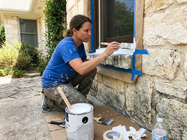 Masking natural limestone on a Central Texas home while cutting in exterior trim